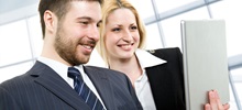 Two business people looking at a notebook together and smiling.